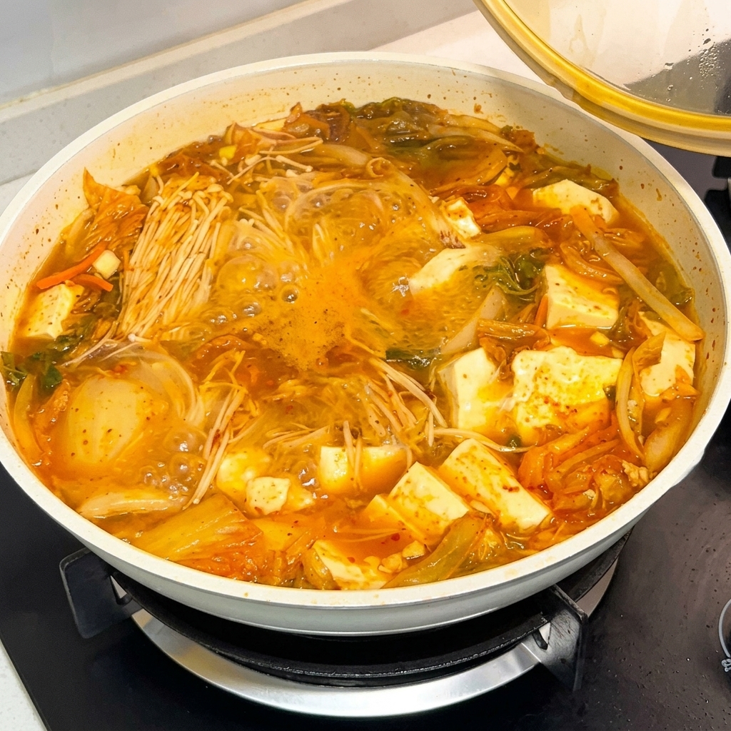 Une cuillerée de sauce à la pâte de piment coréenne versée dans une casserole de soupe bouillante.