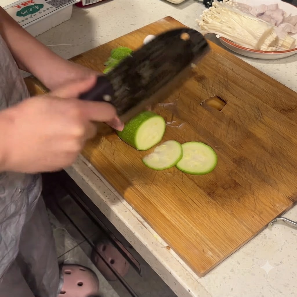 Courgette coupée en rondelles nettes sur une planche à découper en bois avec un grand couteau de boucher.
