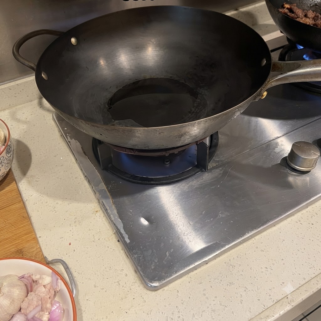 Poitrine de porc et oignon rouge grésillant dans un wok chaud avec de lhuile.