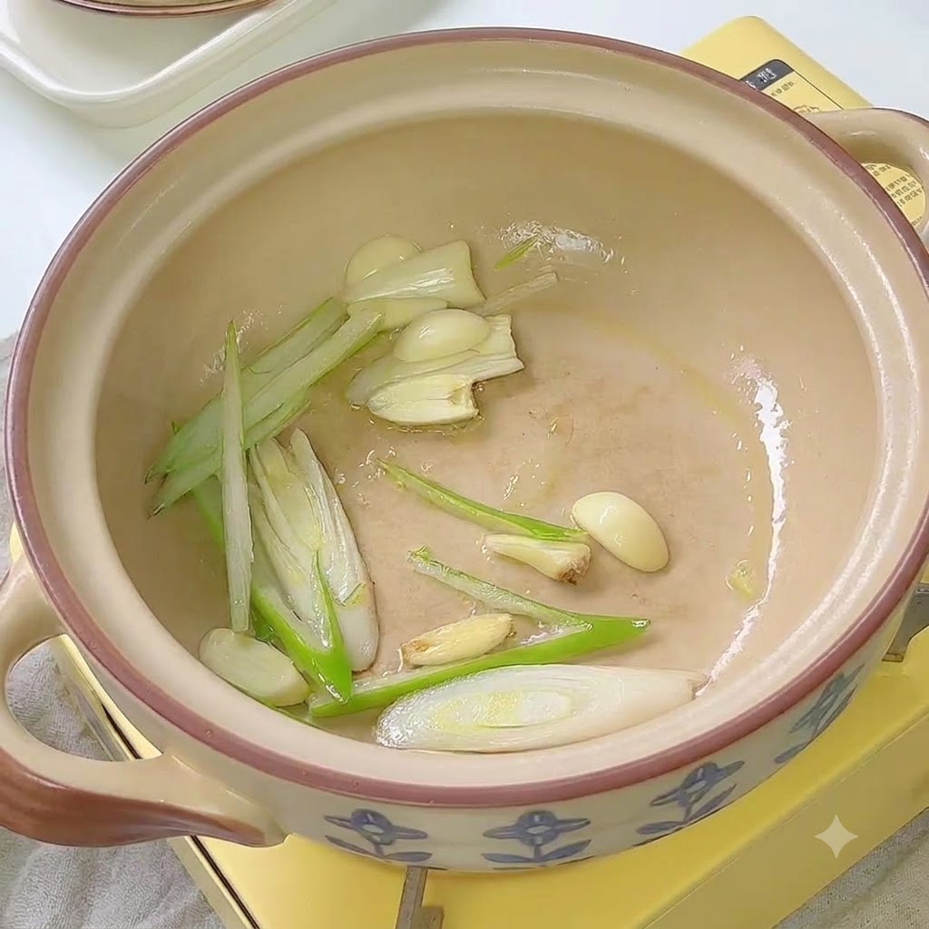 Kimchi en train dêtre sauté avec des cives et de lail à lintérieur dun pot en céramique.