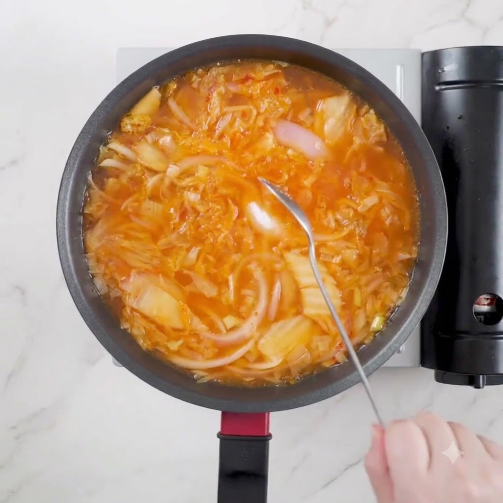 Une cuillère de sauce soja claire versée dans la cocotte de soupe frémissante.