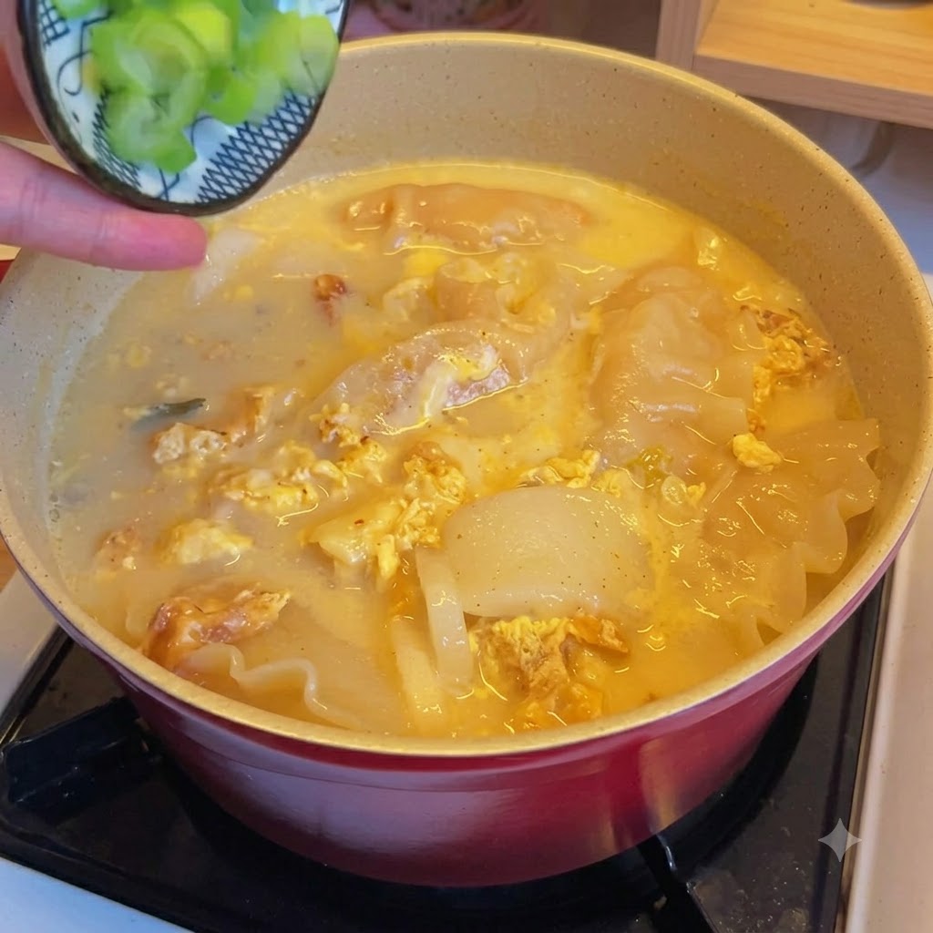 De la ciboule hachée saupoudrée sur une marmite de soupe aux raviolis et kimchi.