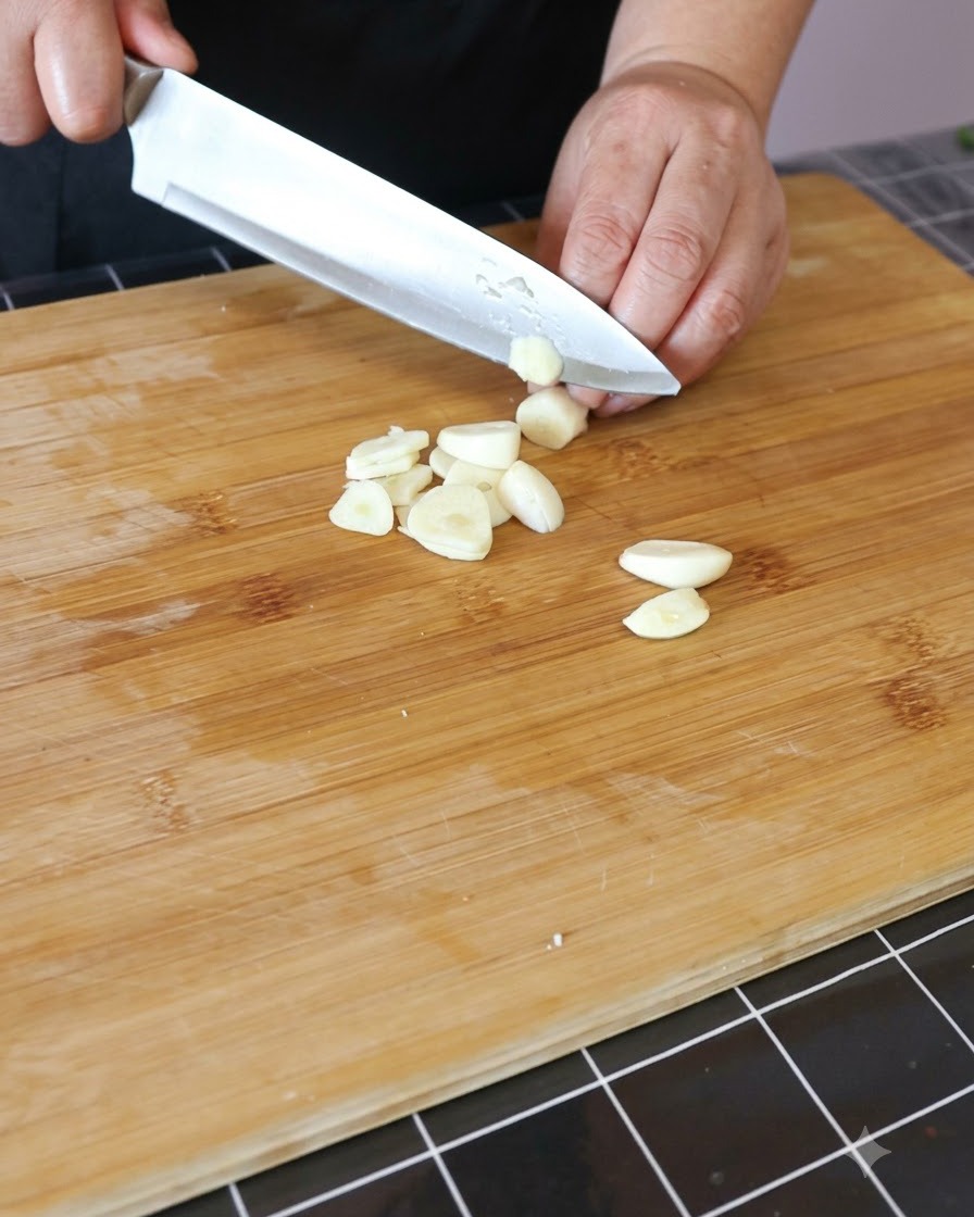 Gousses dail hachées sur une planche à découper en bois.