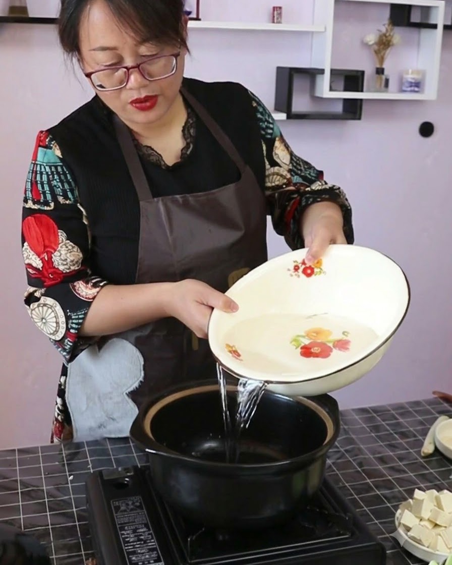 Eau claire versée dun bol décoratif dans une cocotte en céramique noire sur un réchaud portable.