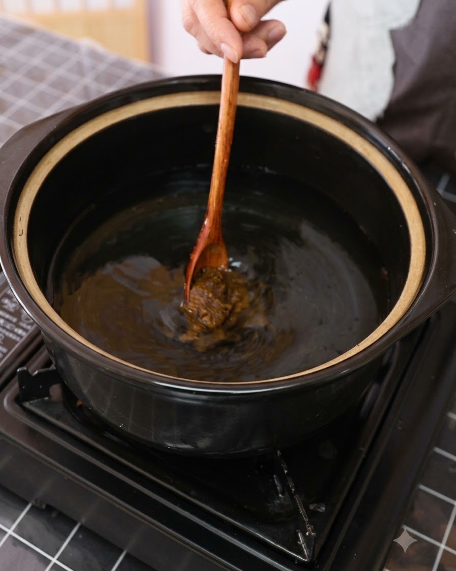 Pâte de soja brune mélangée dans une casserole deau avec une cuillère en bois.