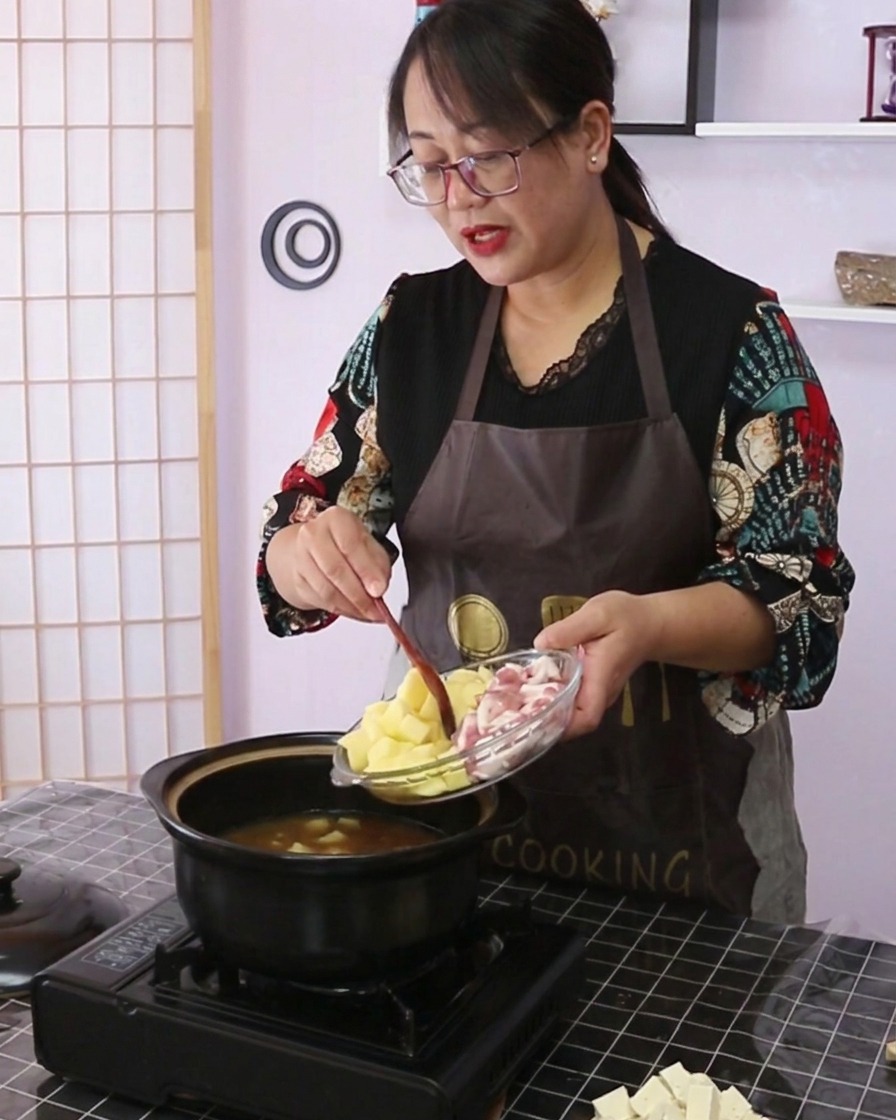 Pommes de terre en dés et poitrine de porc tranchée versées dun plat en verre dans la casserole.