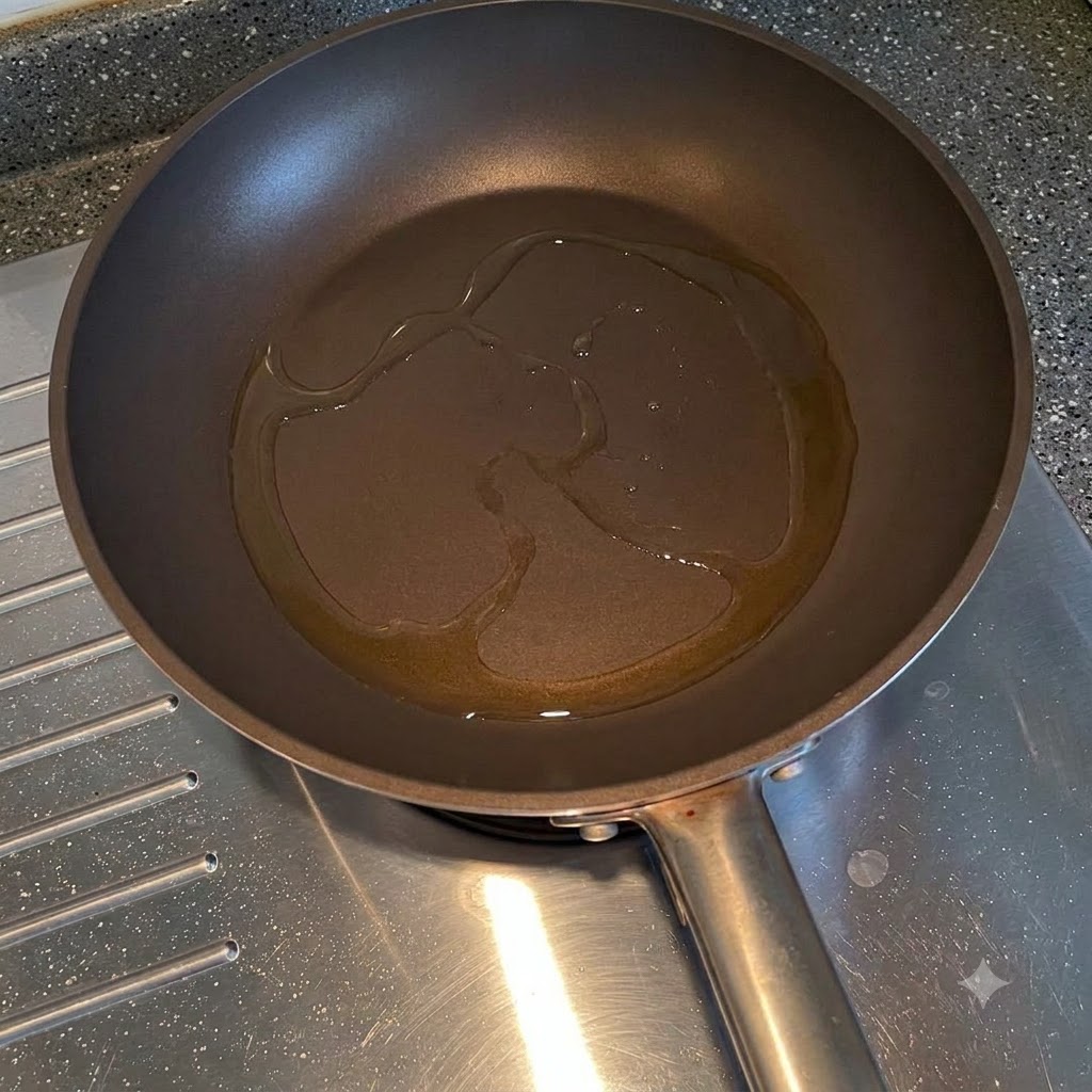Oignons jaunes tranchés frits dans lhuile de cuisson à lintérieur dune poêle.