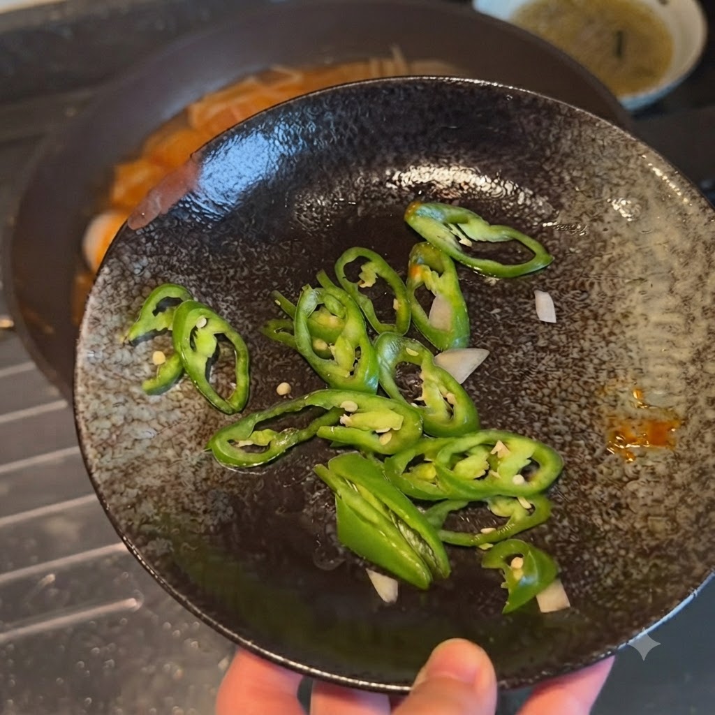 Piments verts fins tranchés disposés sur une assiette décorative sombre avant dêtre ajoutés au plat.