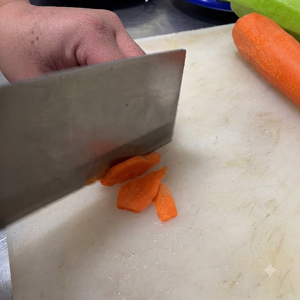 Un couteau coupant un piment vert en rondelles sur une planche à découper blanche.
