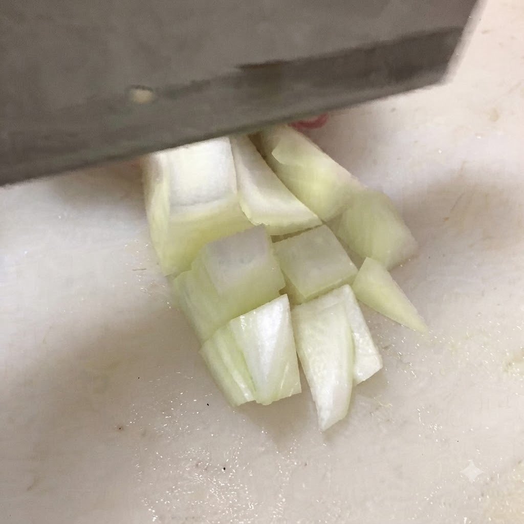 Un couteau coupant du tofu ferme en cubes épais sur une planche à découper blanche.