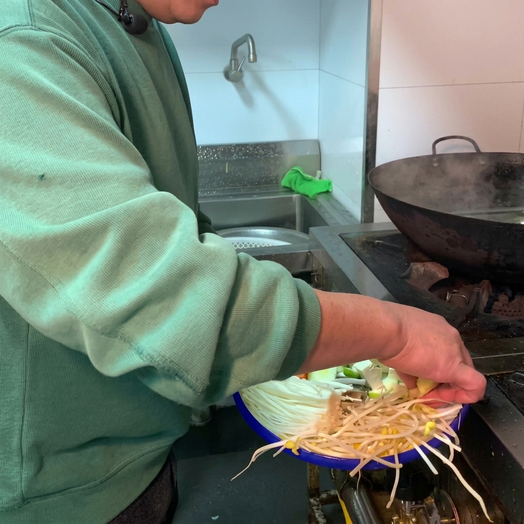 Une variété de légumes frais et de tofu blanc ajoutés dans un pot en terre cuite sombre rempli deau.