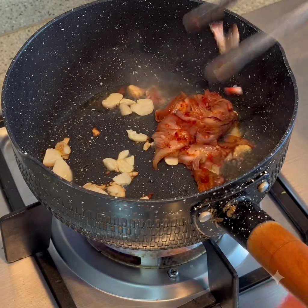Kimchi en train dêtre mélangé et sauté avec de lail frit dans une casserole.