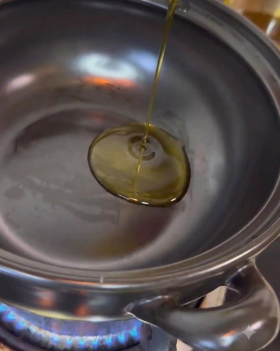 De lhuile de cuisine claire versée au centre dune casserole en acier inoxydable posée sur une flamme bleue active.