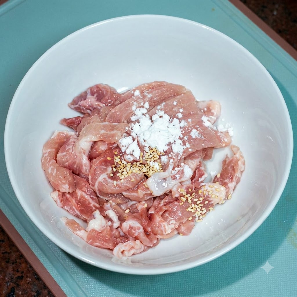 Du porc tranché dans un bol blanc assaisonné avec un peu de bouillon de poulet et dhuile de cuisson.