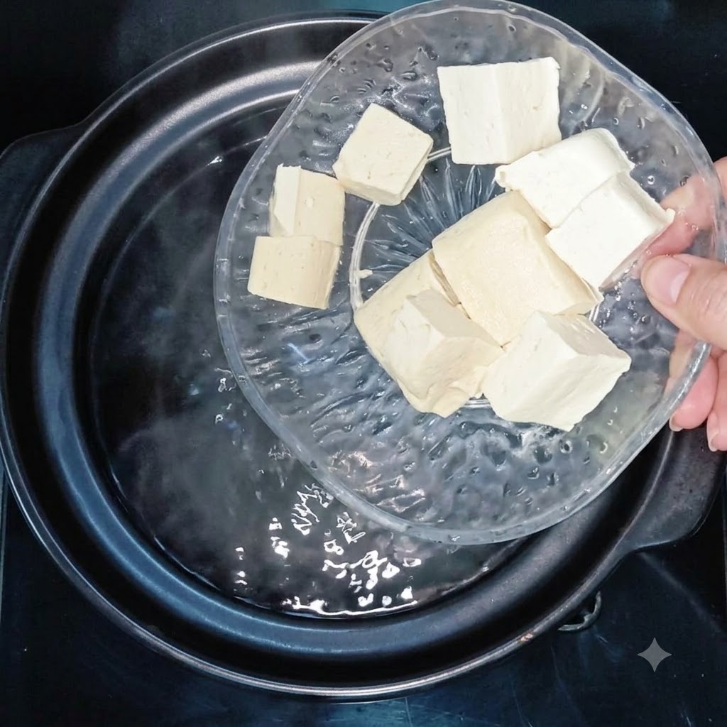 Des cubes de tofu ajoutés dans une casserole deau bouillante.