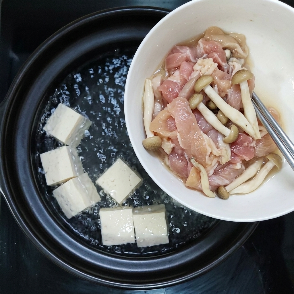 Des tranches de porc assaisonnées et des champignons ajoutés ensemble dans la casserole bouillante.