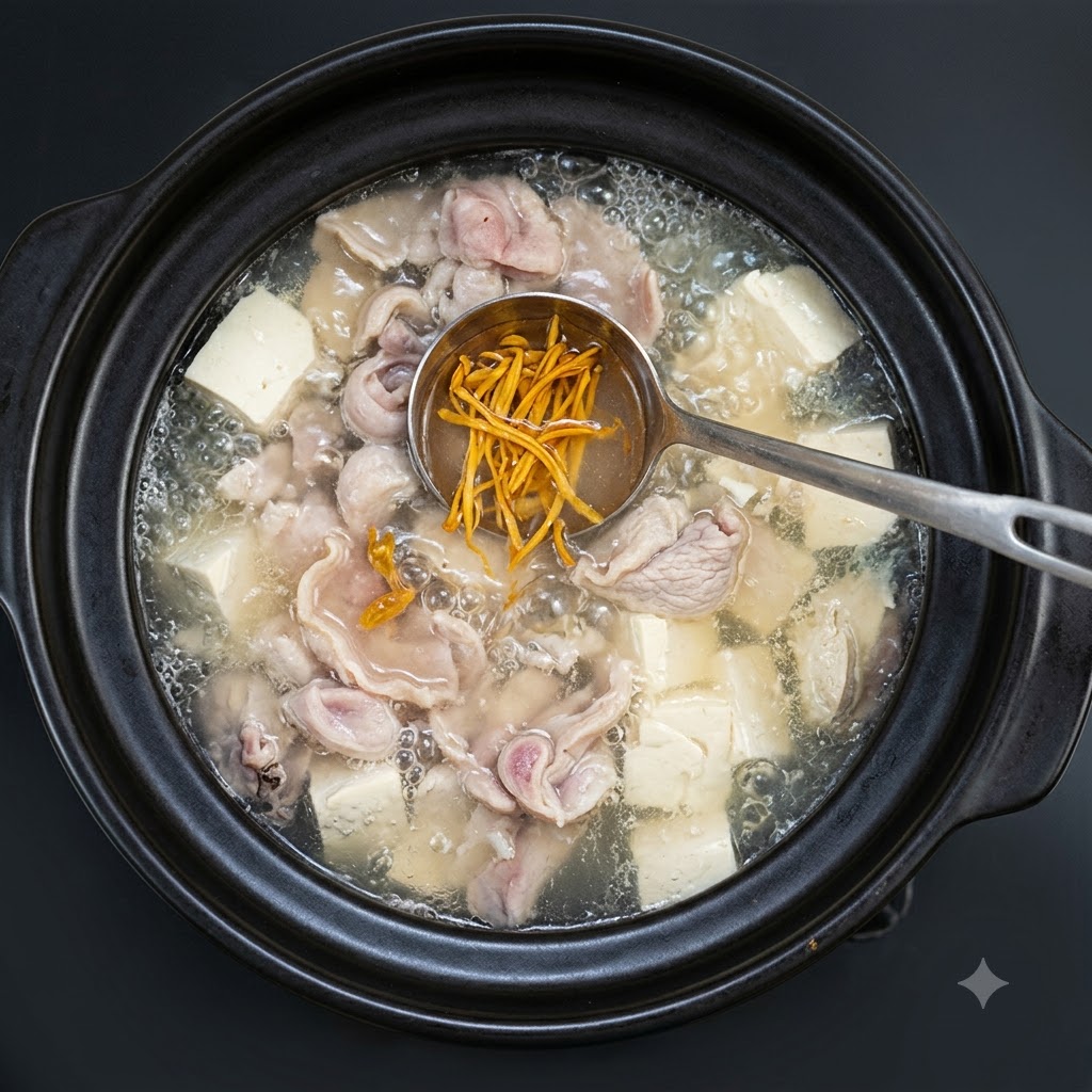 Des oignons verts hachés saupoudrés sur la soupe frémissante dans le plat en terre cuite.