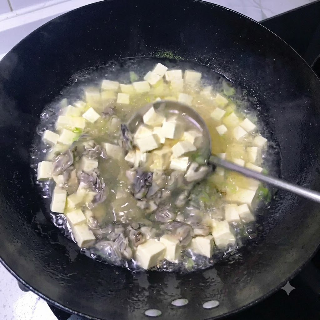 Une louche remuant un bouillon laiteux frémissant rempli de dés de tofu et dhuîtres cuites dans un wok noir.