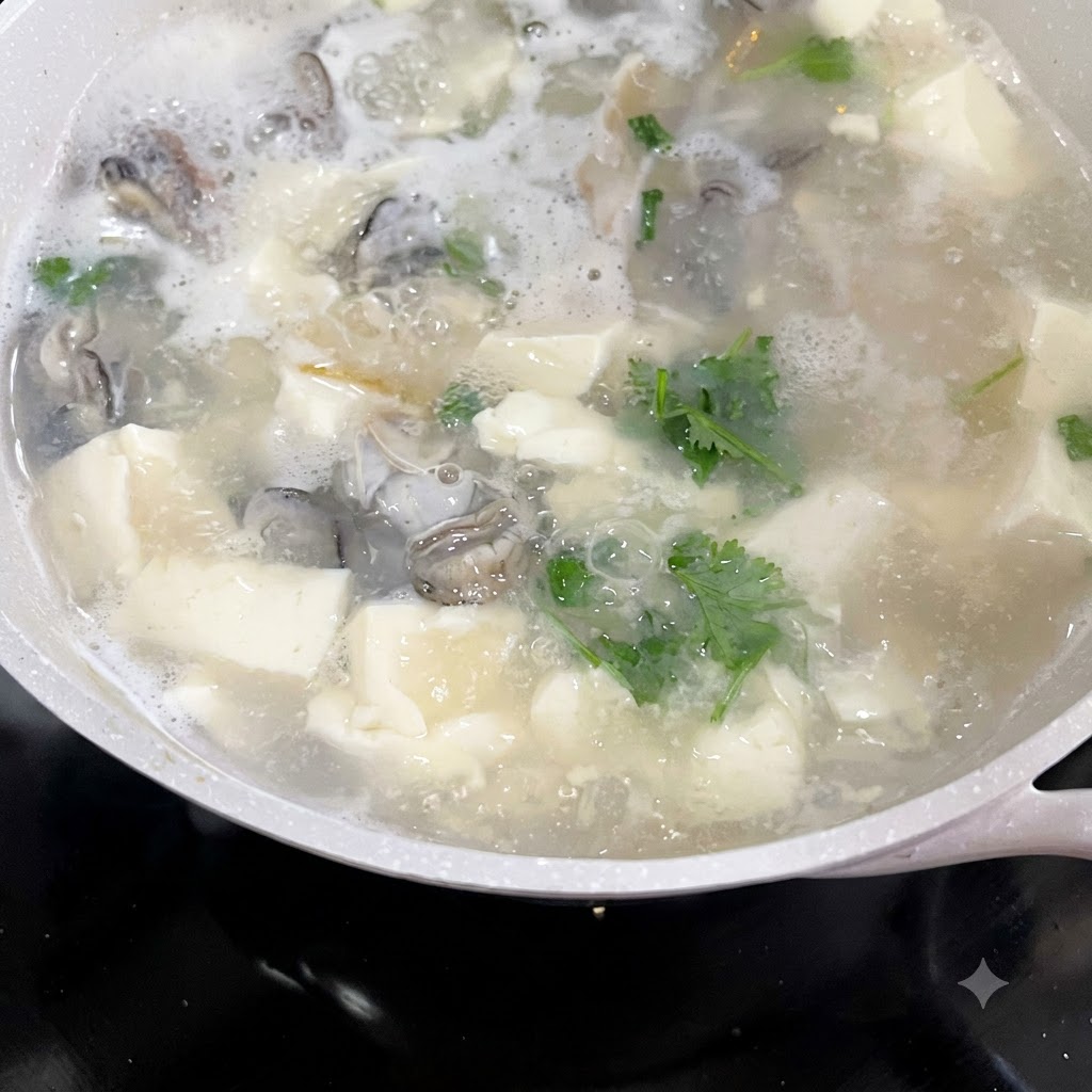 De la coriandre et des oignons verts hachés ajoutés dans une casserole bouillante de soupe dhuîtres et de tofu.