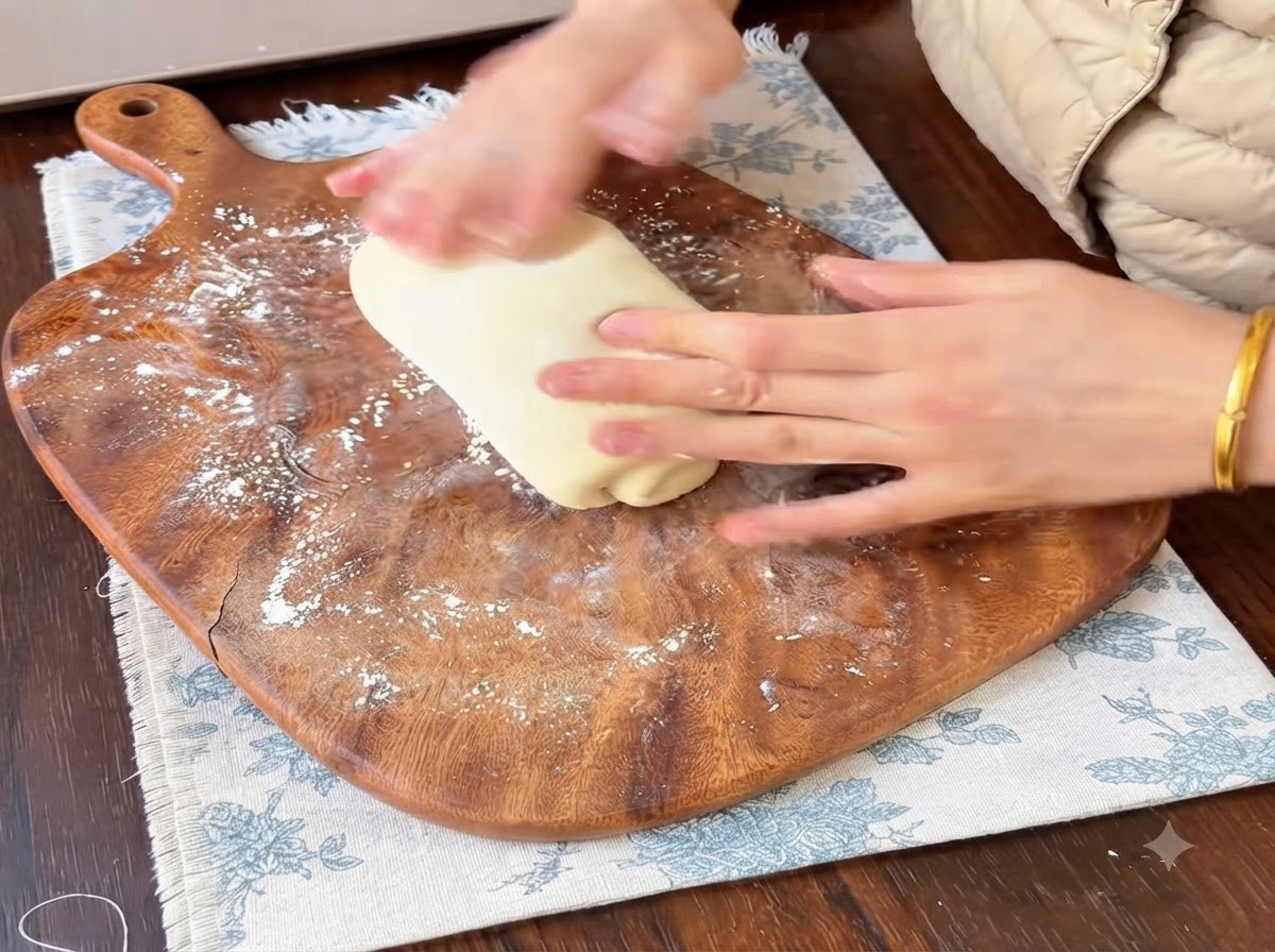 Mains façonnant des boules de pâte sur une planche à découper farinée.