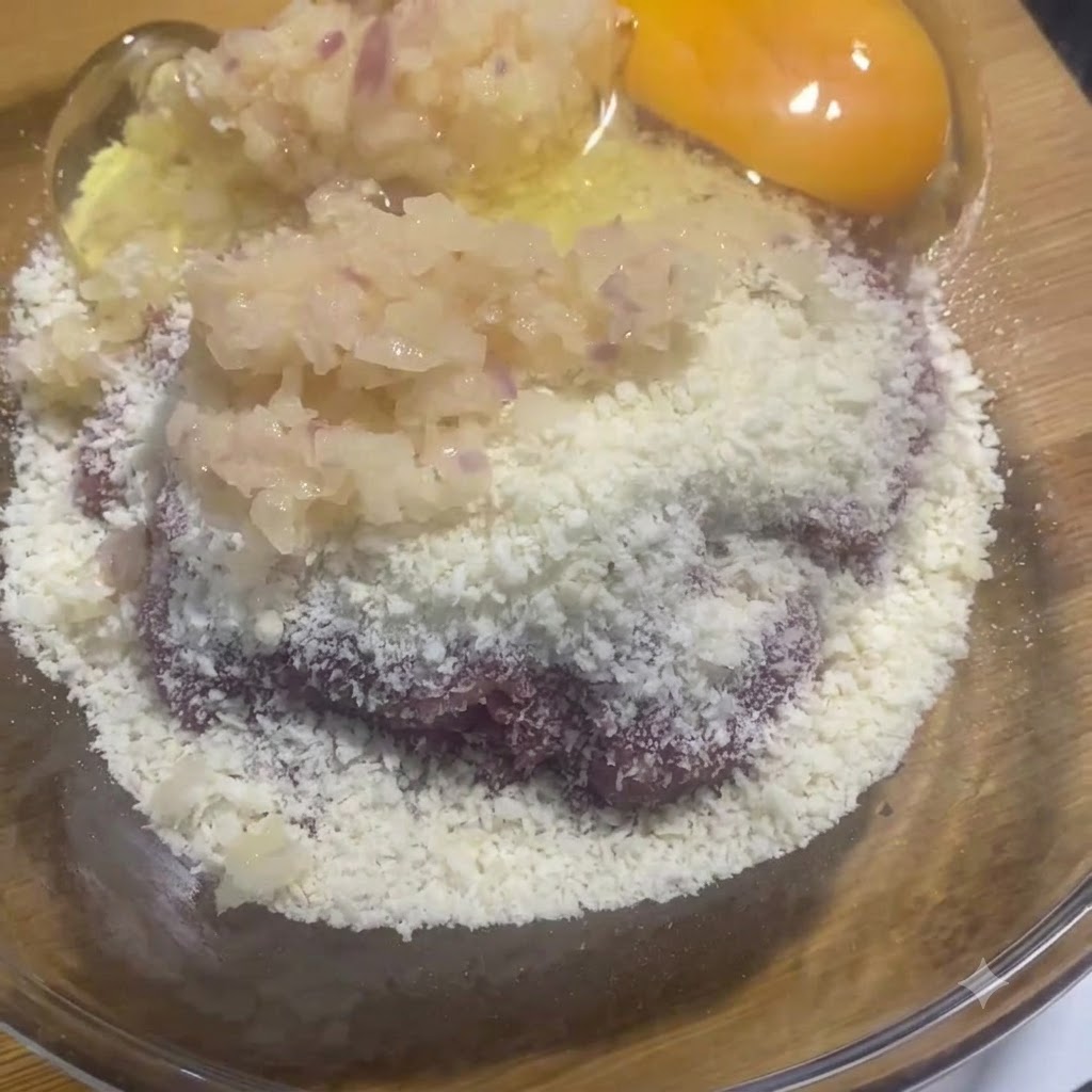 Un jaune et un blanc dœuf cru reposant dans le bol en verre à côté du mélange de viande et doignons.