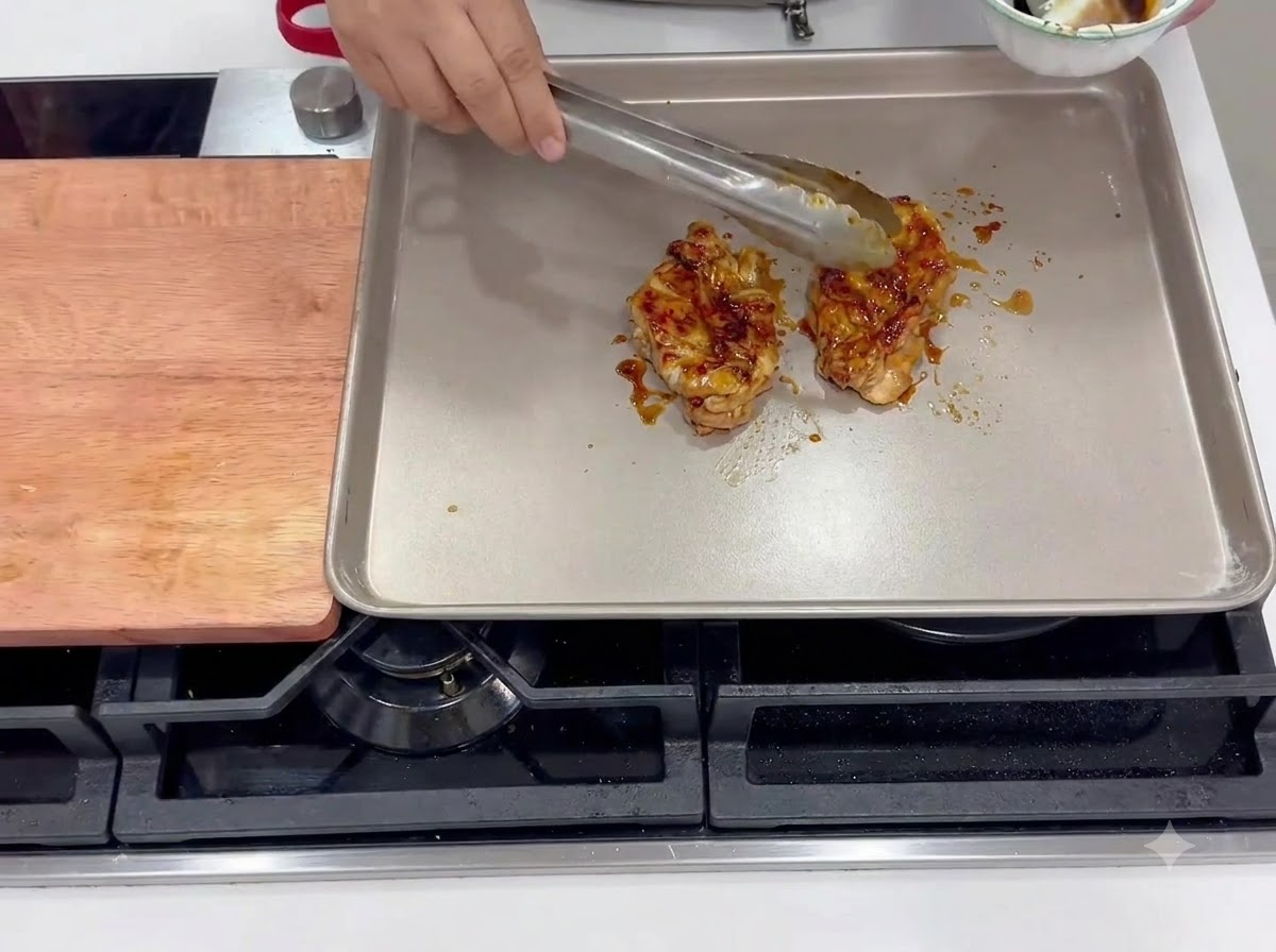 Hauts de cuisse de poulet marinés en train de cuire côté peau dans une poêle carrée chauffée.