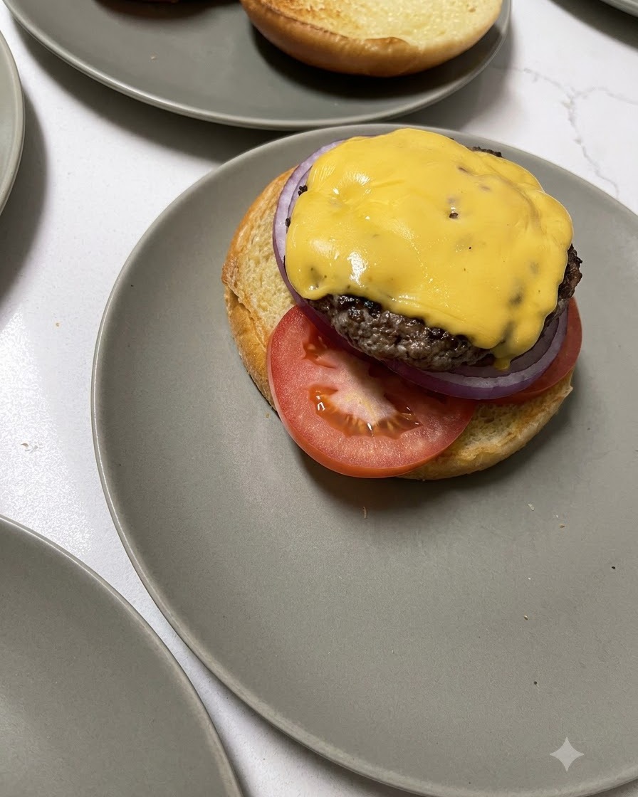 Un steak de bœuf garni de fromage transféré dune spatule en bois vers une base de burger.