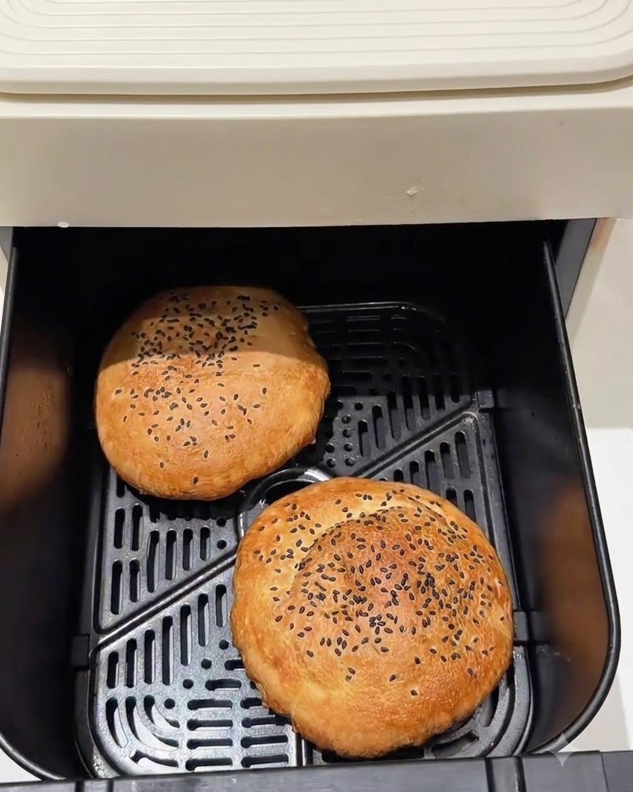 Pains à burger cuits assis à lintérieur dun panier de friteuse à air.