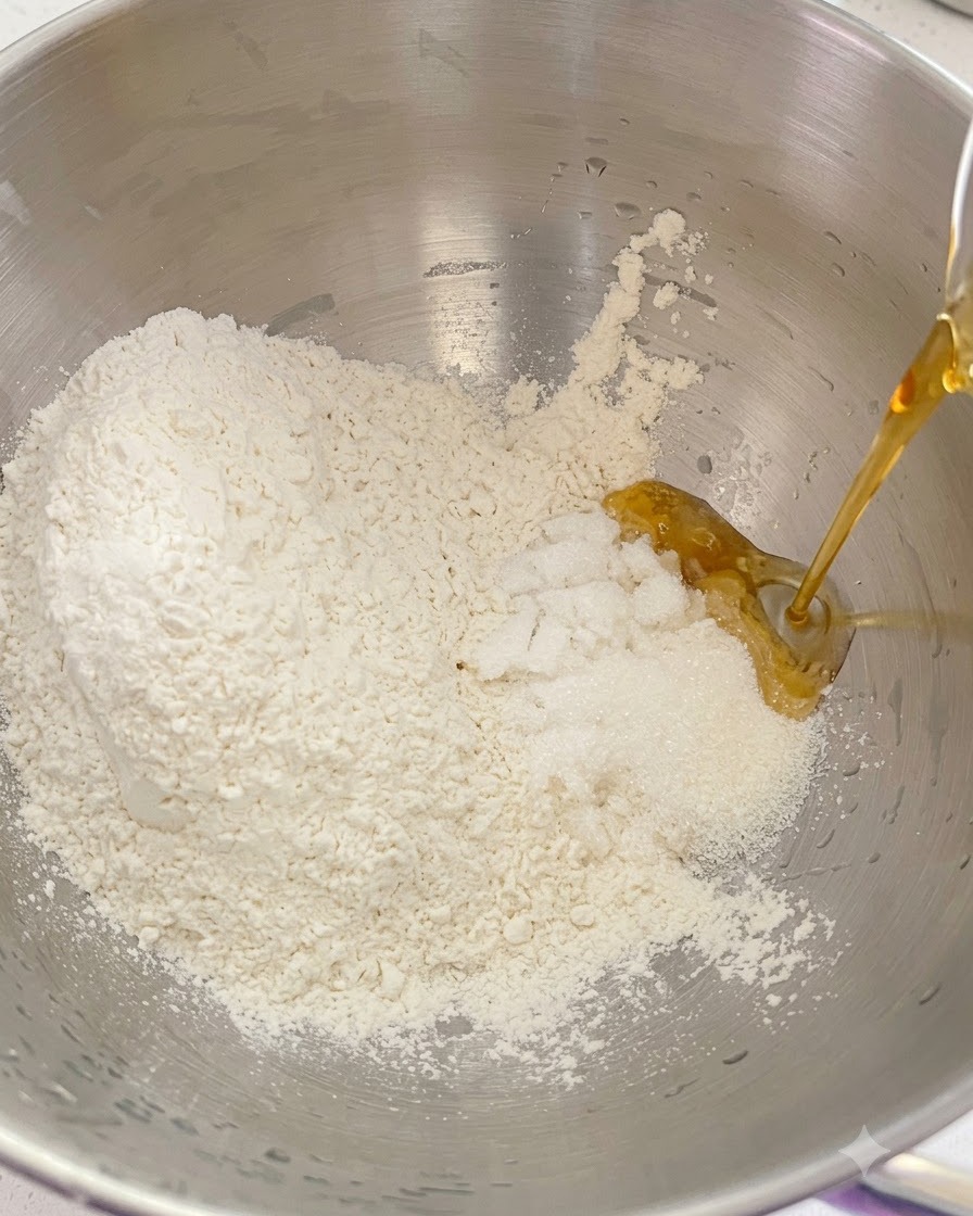 Farine sèche, sucre et ingrédients liquides versés ensemble dans le bol dun robot pâtissier en métal.