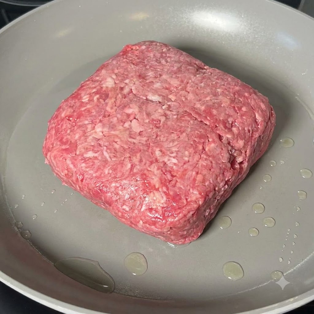 Du bœuf haché en train dêtre cuit et émietté avec une spatule en bois dans une large poêle.
