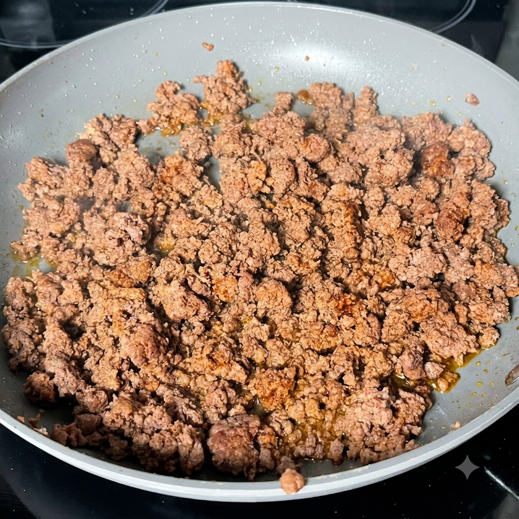 De la sauce Worcestershire foncée versée sur du haché de bœuf doré dans une poêle.