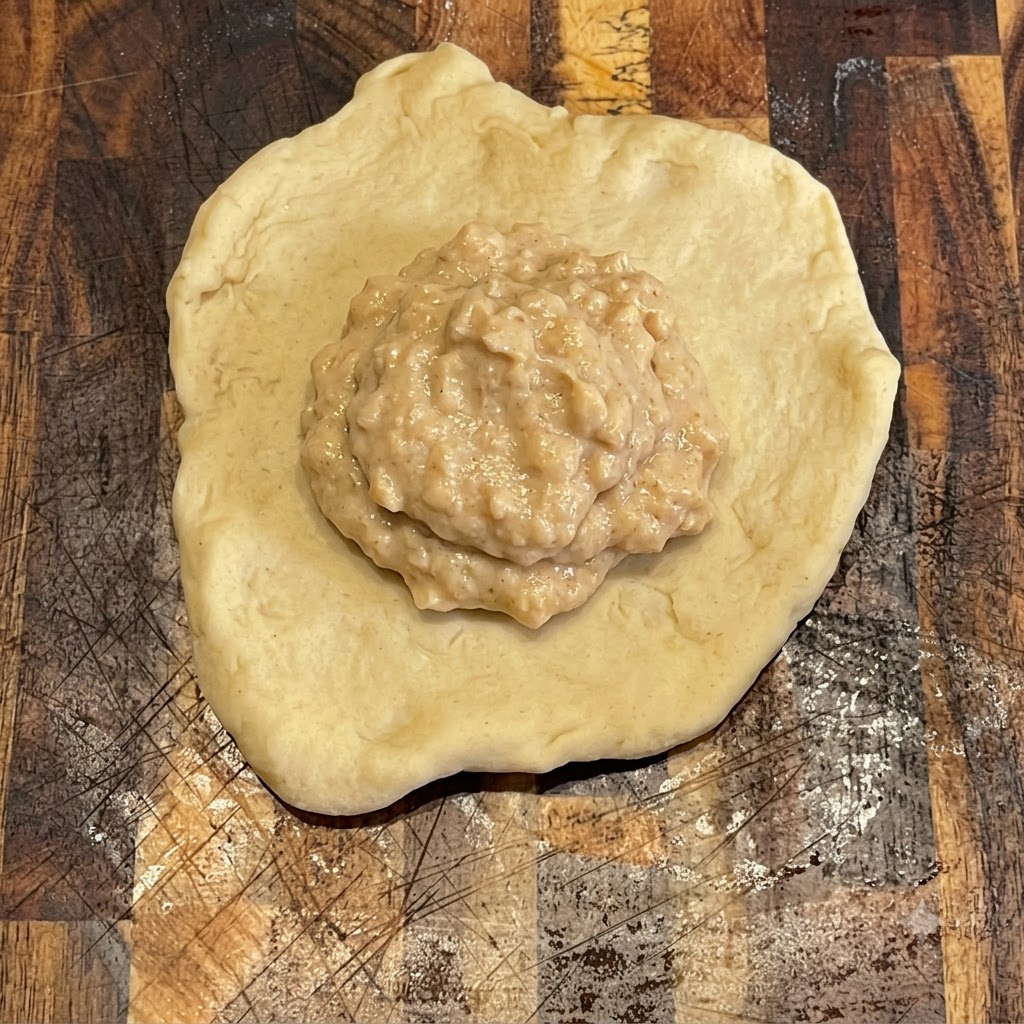 De la sauce burger étalée proprement sur le dessus dun morceau de pâte rond et plat sur une planche en bois.