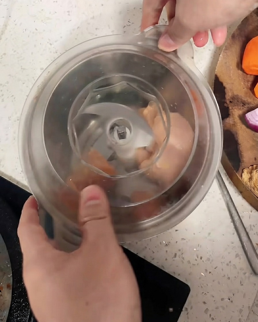 Un robot culinaire dont le couvercle est fixé sur des morceaux de poulet.