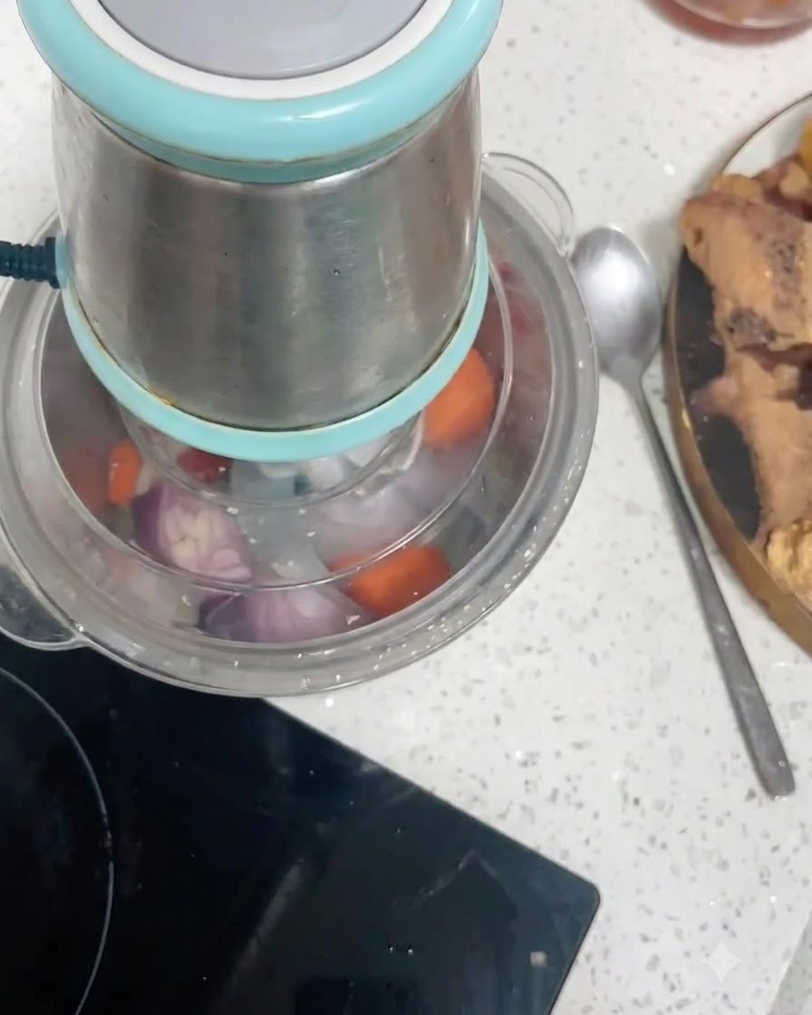 Morceaux de carottes et doignons rouges en train dêtre hachés à lintérieur du récipient dun robot culinaire.