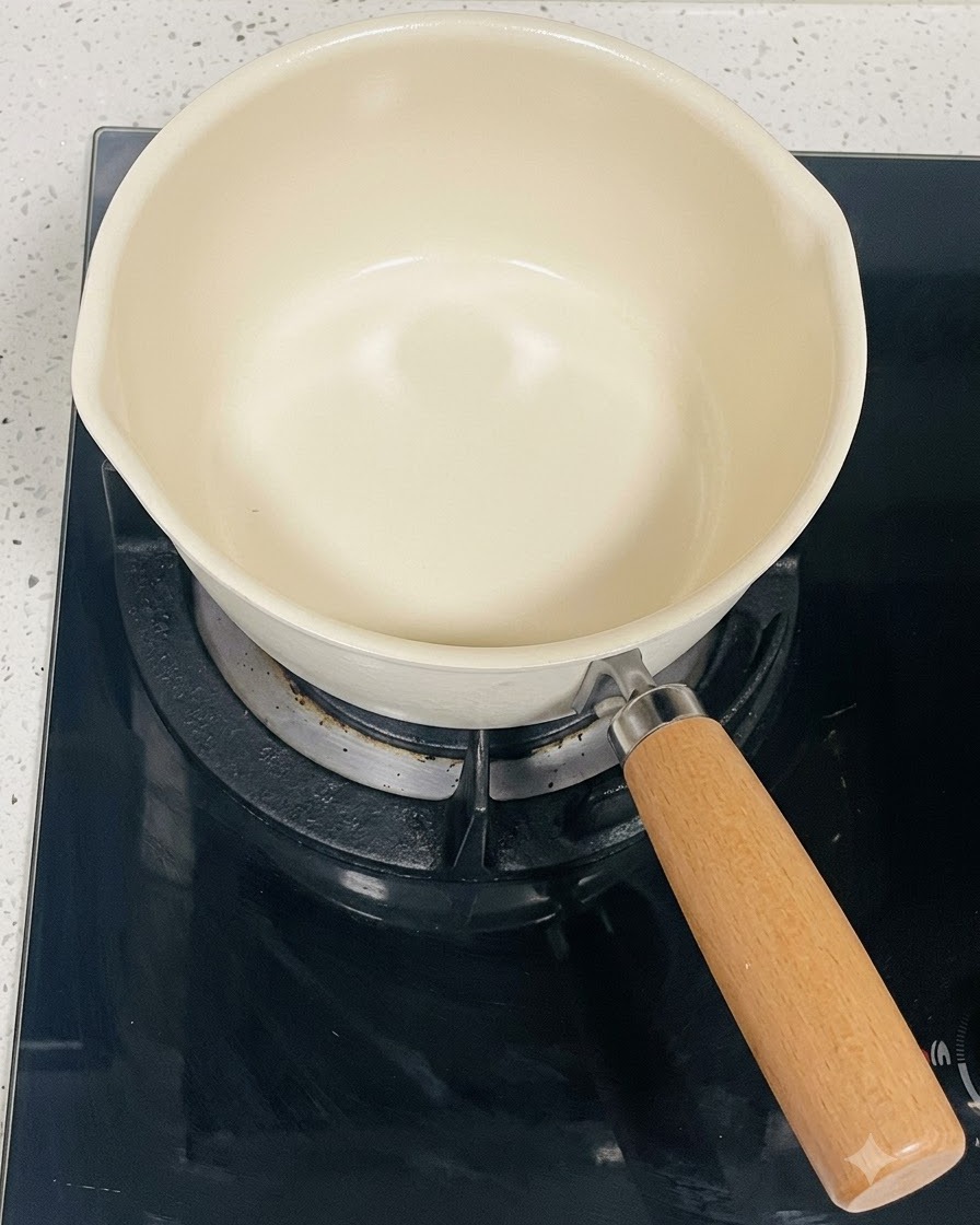 Une casserole vide de couleur crème posée sur un brûleur de table de cuisson à induction noir.