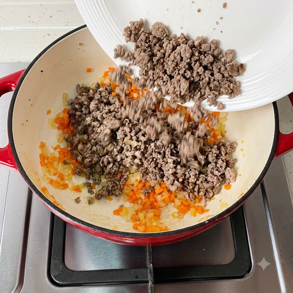 Viande hachée cuite rajoutée dans la poêle contenant les légumes.