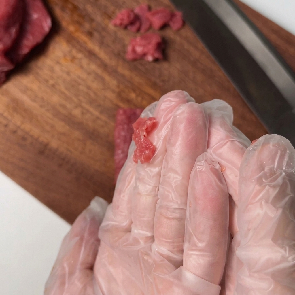 Filet de bœuf tranché mélangé à la main avec des assaisonnements dans un bol.