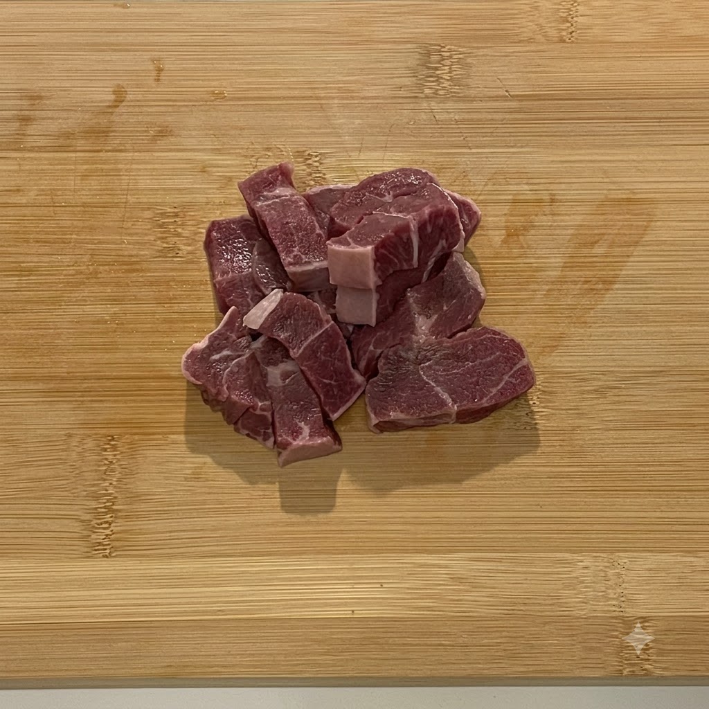 Morceaux de bœuf cru placés dans le bol en acier dun robot culinaire.
