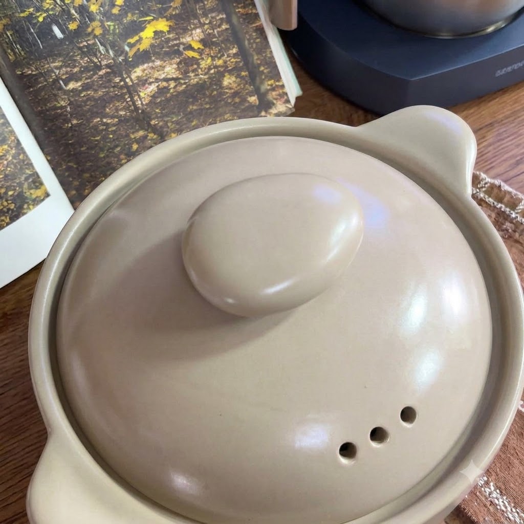 Des tomates fraîches disposées sur une grille à côté dun pot en céramique.