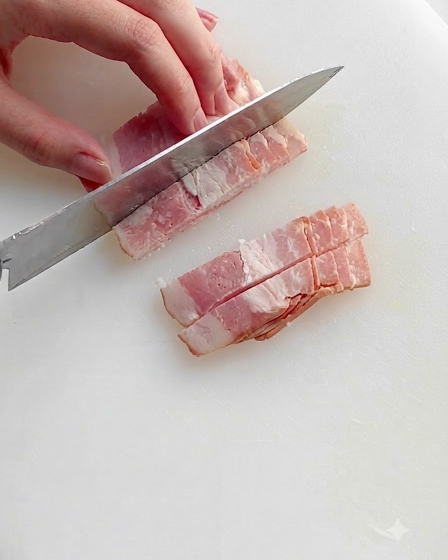 Des morceaux de bacon hachés en train de frire dans une poêle chaude avec un filet dhuile, montrant de la graisse grésillante et des bords dorés.