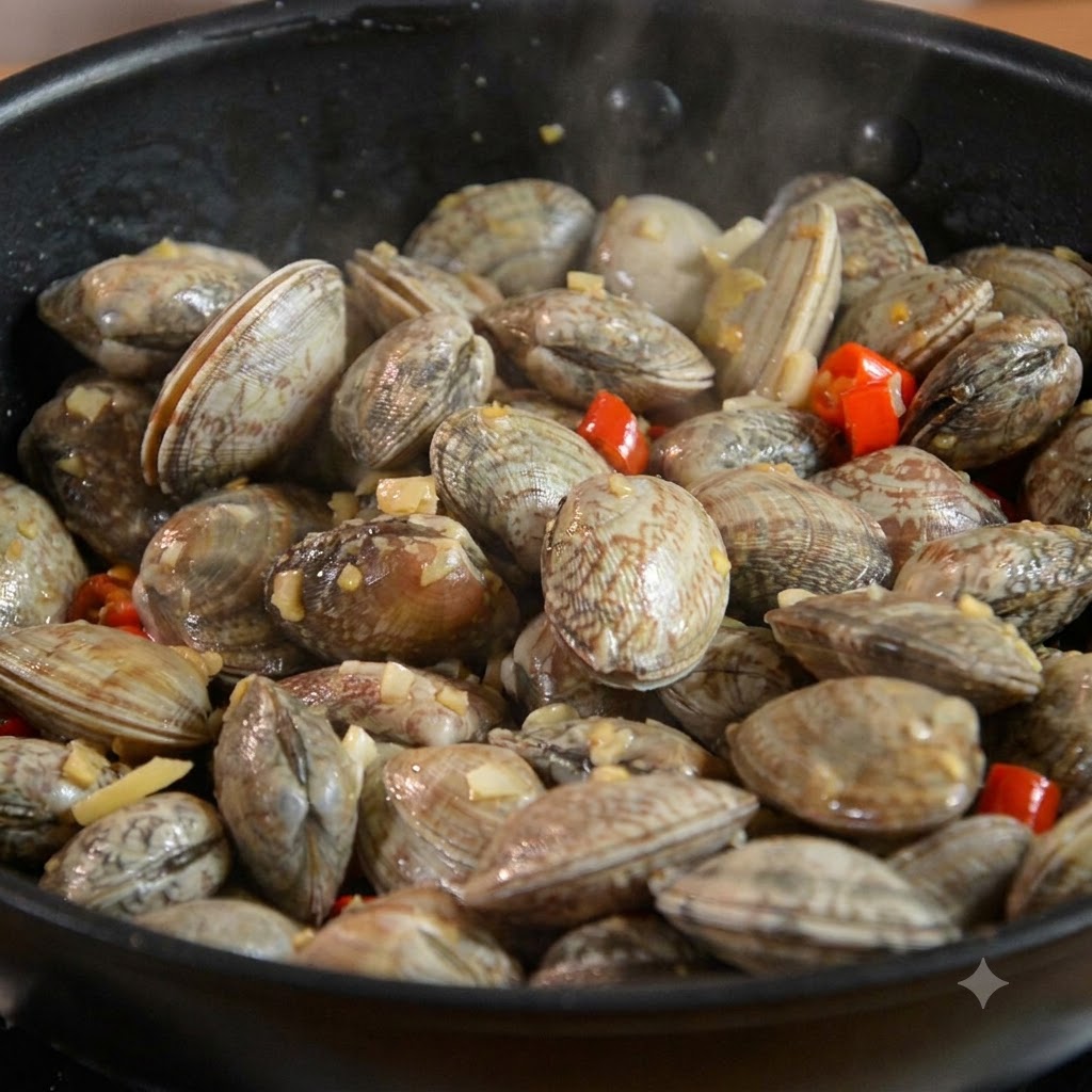 Des palourdes mélangées avec de lail et du piment à lintérieur dune poêle noire.