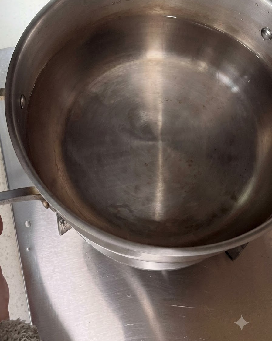 Grande casserole en acier inoxydable remplie deau placée sur un feu de cuisinière.