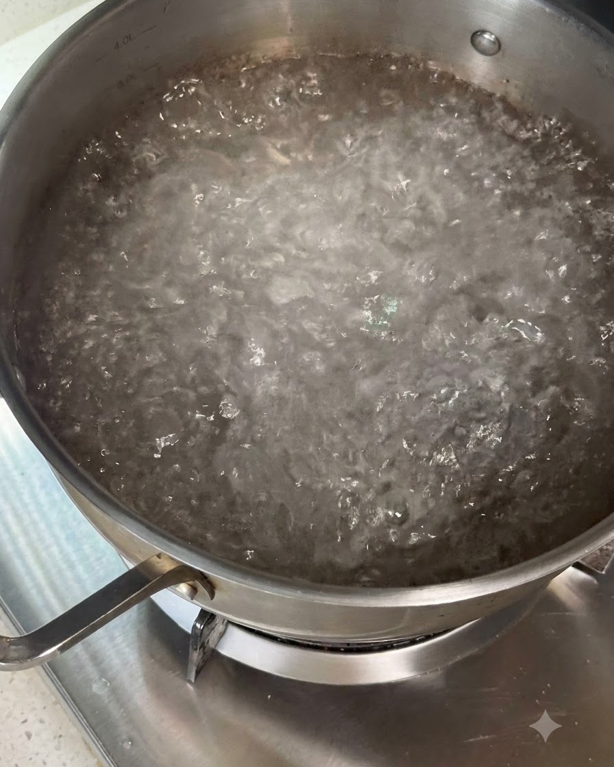 Pâtes sèches remuées dans une casserole deau bouillante à laide dustensiles.