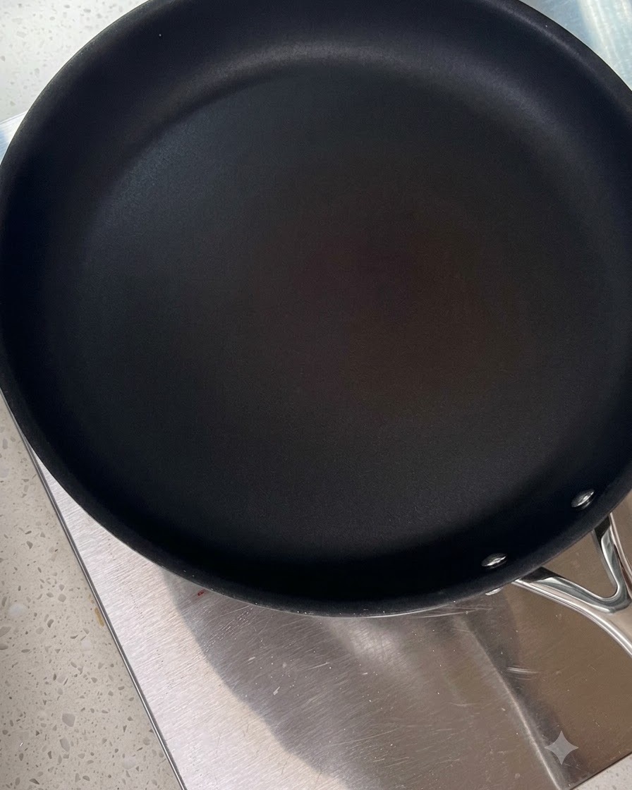 Poêle à frire noire propre en train de chauffer sur une plaque de cuisson.