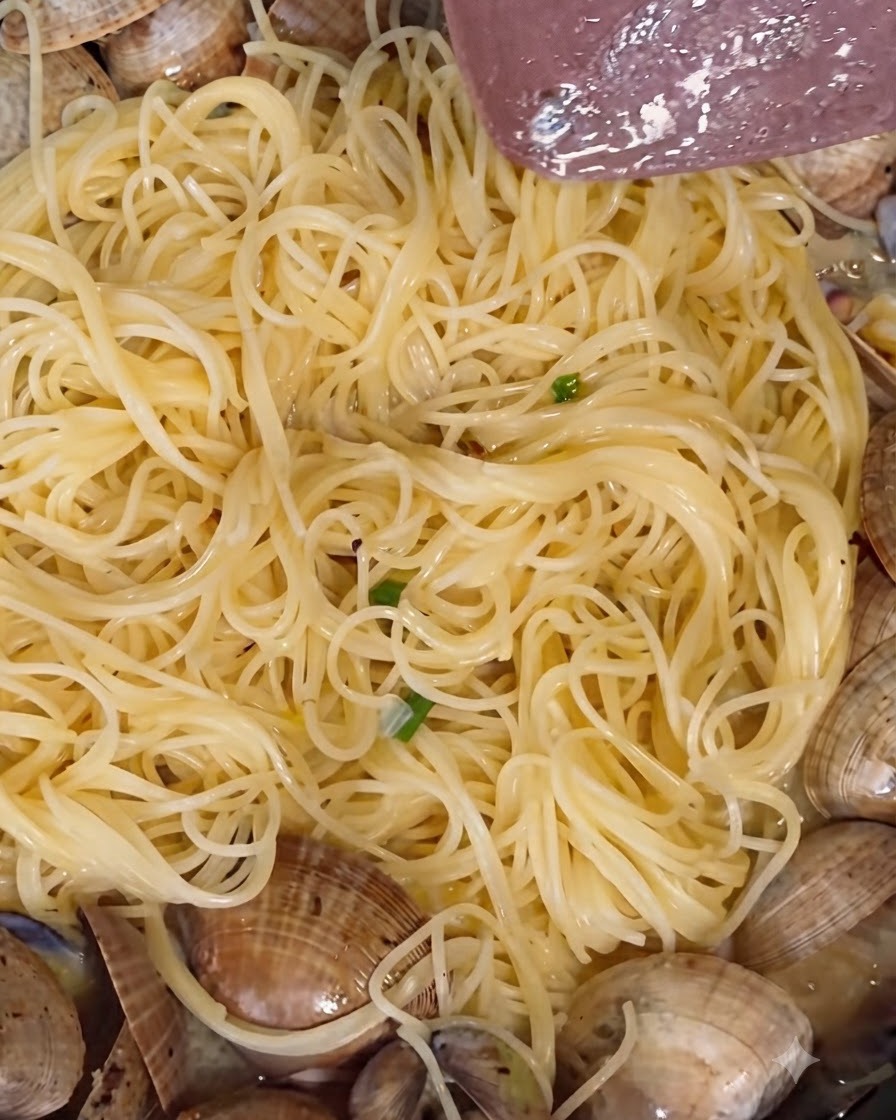 Poudre de poivre blanc et poivre noir fraîchement moulu saupoudrés sur les palourdes mijotant dans une poêle.