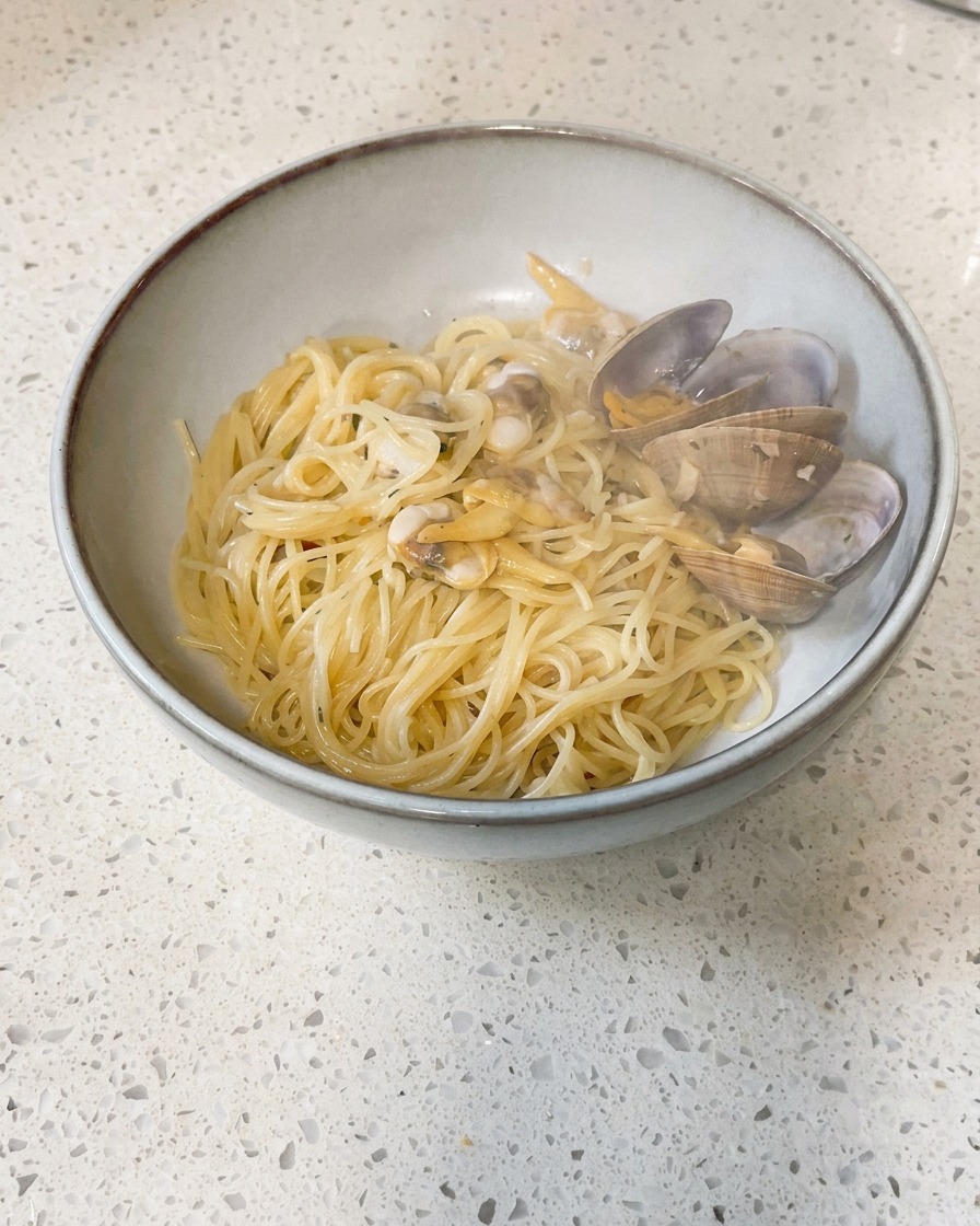 Petits morceaux de beurre froid déposés dans une poêle contenant des palourdes cuites et leur bouillon.