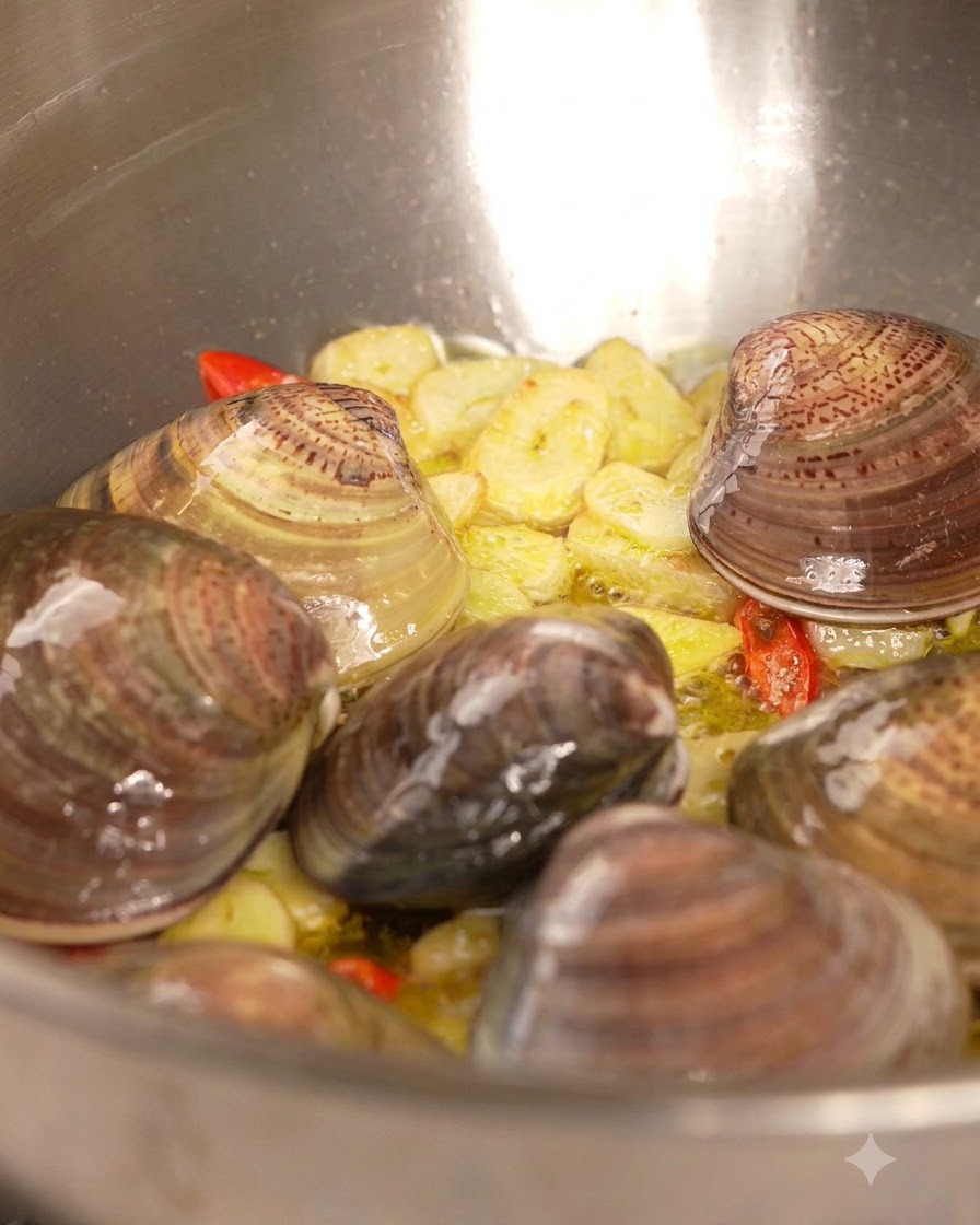 Du vin blanc versé depuis une bouteille dans une poêle remplie de palourdes, dail et de piment.