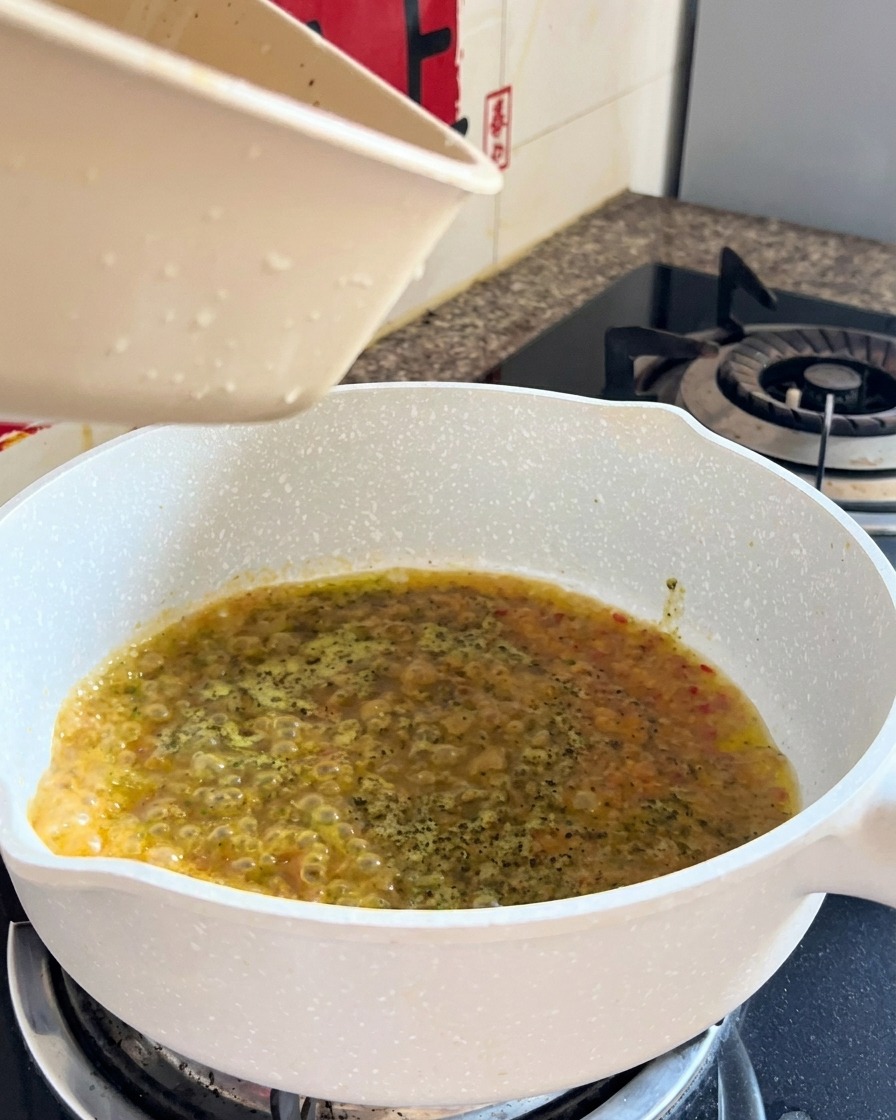 Spaghetti cuits et liquide en cours de combinaison dans une poêle lors du mélange final.