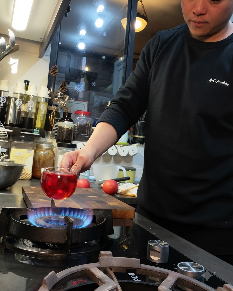 Une tomate tenue au-dessus de la flamme bleue dune cuisinière à gaz avec une entaille en croix sur sa surface.