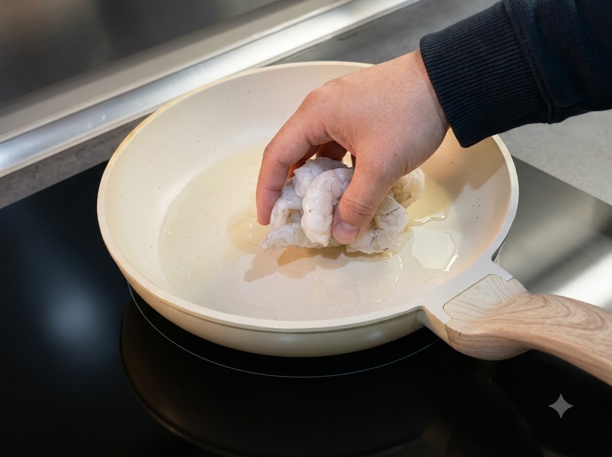 Crevettes décongelées déposées dans une poêle huilée pour la cuisson.